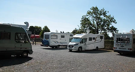 Mehrere Wohnmobile stehen auf dem Wohnmobilparkpaltz am Einbecker Schwimmbad. Im Hintergrund ist die 35 m Röhrenrutsche vom Schwimmbad zu sehen.