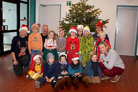 Gruppenaufnahme der Waldzwerge vor einem geschmückten Weihnachtsbaum im Eingangsbereich des Hallenbads